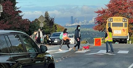 Photo of children crossing a street crosswalk with a school bus in the background