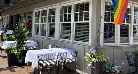 Image of a sidewalk patio with two tables covered by tablecloths.