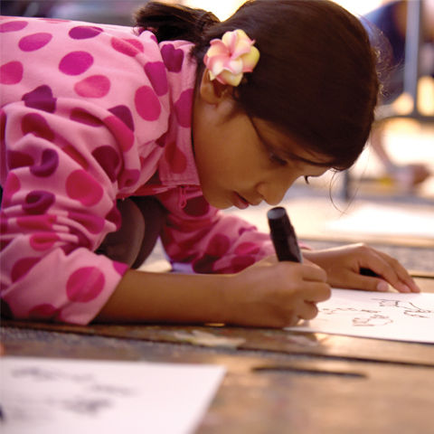 girl in a pink polka dot top drawing