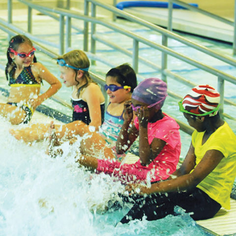 five children sitting on the edge of a pool