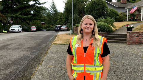 A city worker stands in front of a house on the sidewalk