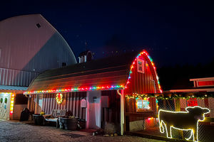 Image of barn, with multi-color string of lights around roof